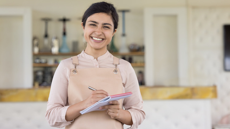Smiling waitress writing in notepad