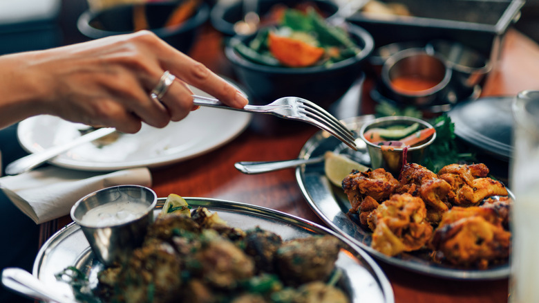 Woman picking food off plate at Indian restaurant