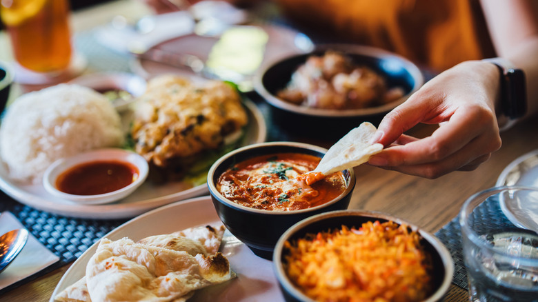 Woman sampling Indian food at restaurant