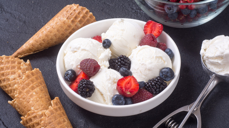 Scoops of vanilla ice cream are mixed with berries