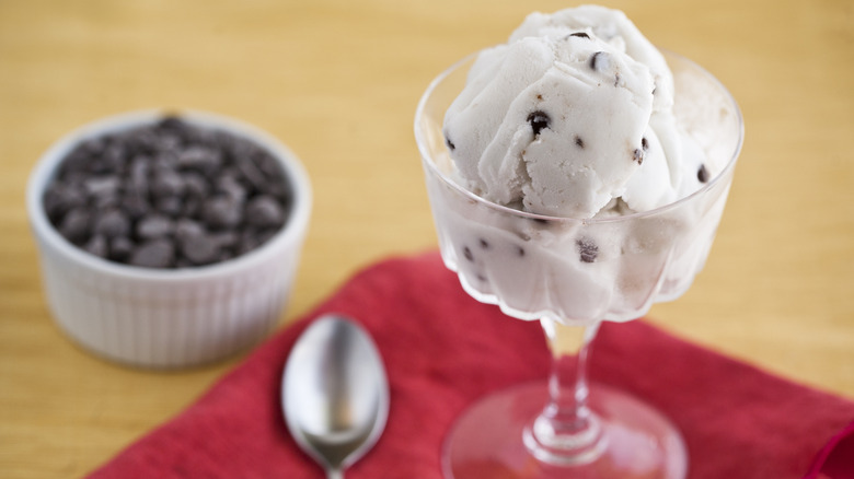 A dish of ice cream with chocolate chips is next to a dish of chocolate chips