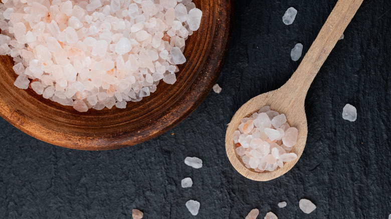 A spoon of Himalayan pink salt sits next to its dish