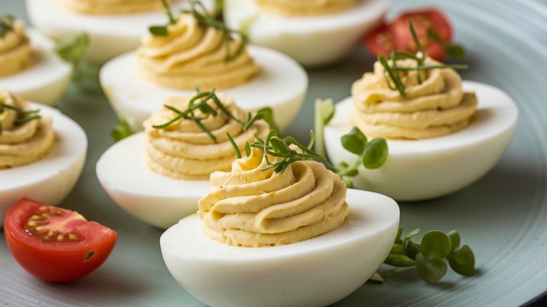 A plate of deviled eggs with herb garnish