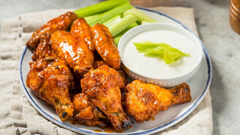 A plate of buffalo wings with ranch and celery