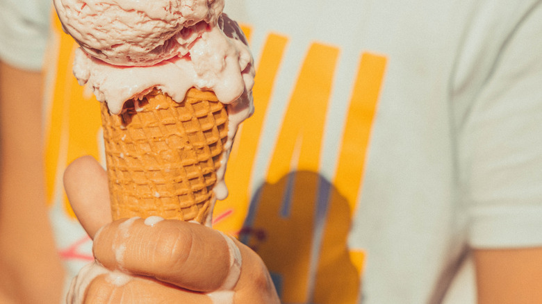 Person holding a melting ice cream cone