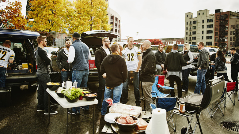 People eating food and hanging out at a tailgate party