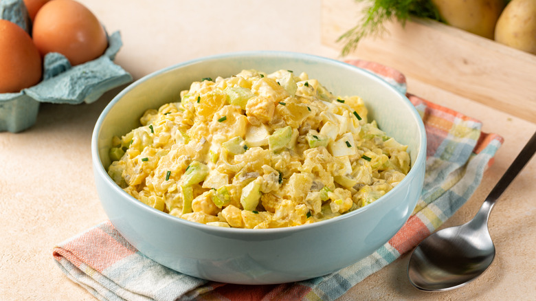 A bowl of potato salad with mustard, mayo, and eggs with herb garnish
