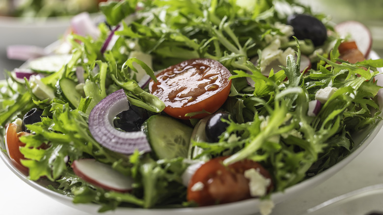 A green salad with tomatoes, red onion, and cucumbers