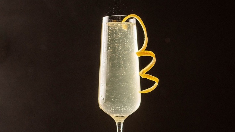 French 75 in champagne glass with lemon twist on a black background