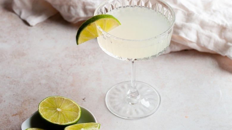 gimlet in coupe glass with limes in a white background