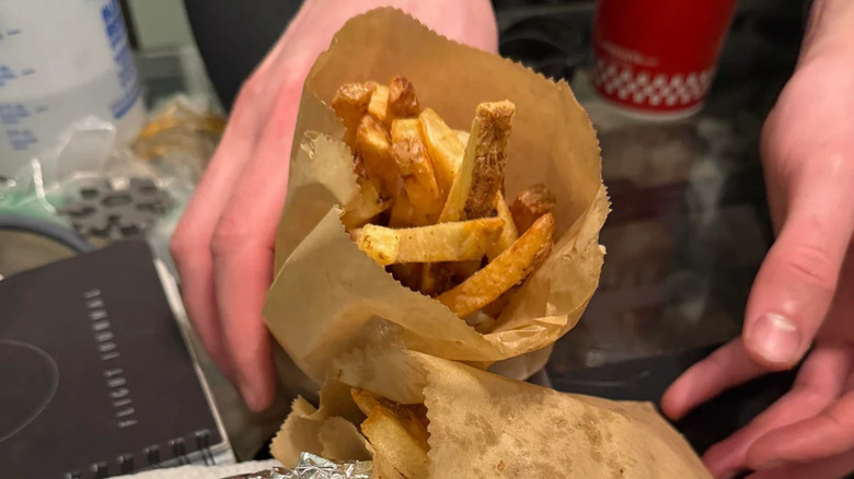 A person holding a nag of fries from Five Guys