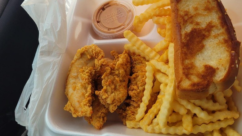 A takeout container of Raising Cane's chicken fingers, fries, and Texas toast