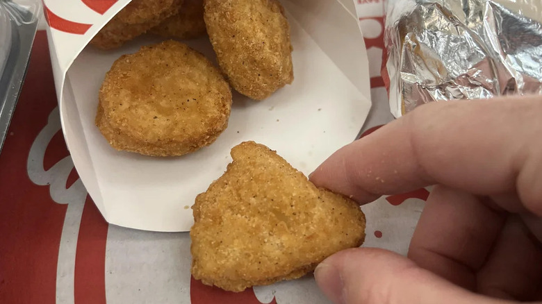 A person holding a chicken nugget from Wendy's