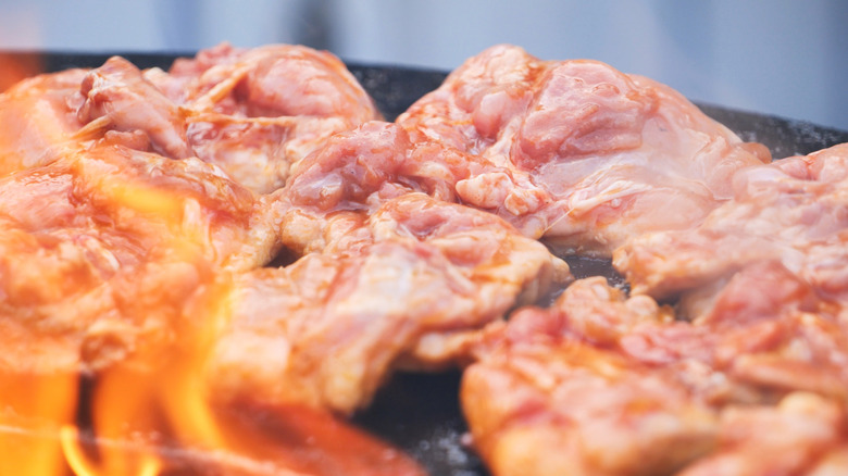 Grilling chicken thighs on outdoor barbecue