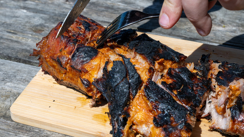 Charred pork tenderloin being sliced