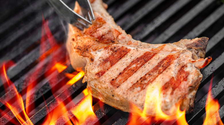 Grilled pork chop with tongs