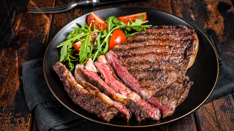 Wagyu steak, sliced, on a plate with a salad