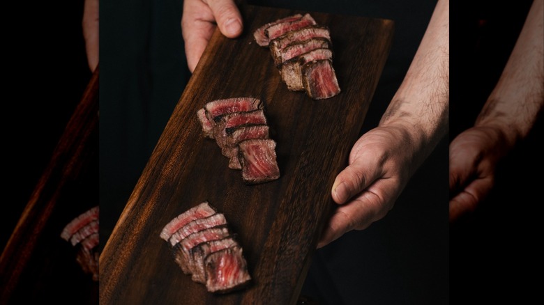 Hands holding a wooden tray showcasing three Wagyu options from Metropolitan Grill