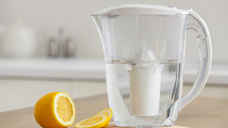 A water filter pitcher on a kitchen countertop next to a fresh lemon