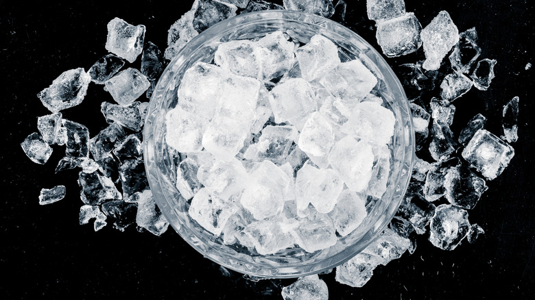 A glass of whiskey filled with ice on a wooden surface