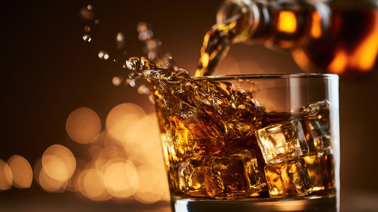 Whiskey splashing out of a glass filled with ice
