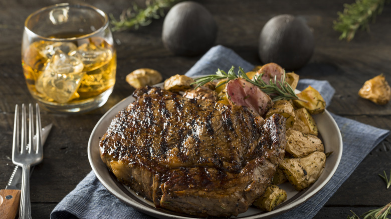 A steak dinner with a whiskey beverage