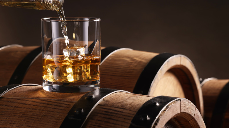 A glass of whiskey on top of oak barrels