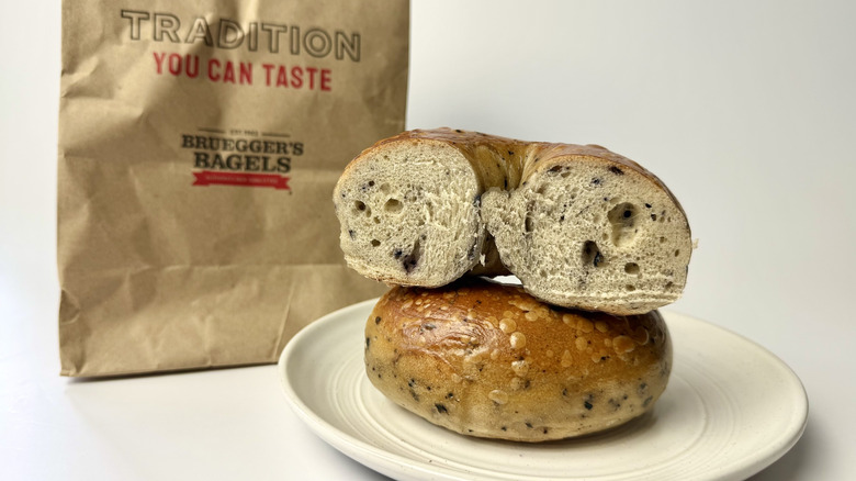 Bruegger's Bagels blueberry bagel on a white plate in front of the packaging