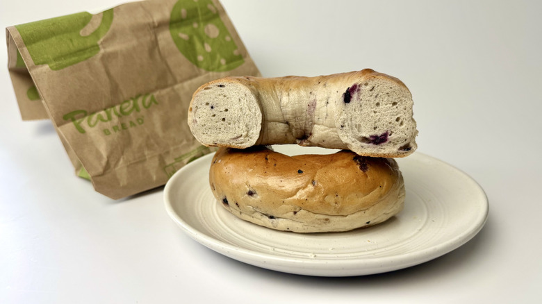 Panera Bread blueberry bagel on a white plate in front of the packaging