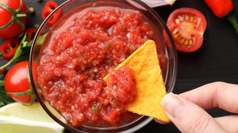 Hand dipping chip into salsa