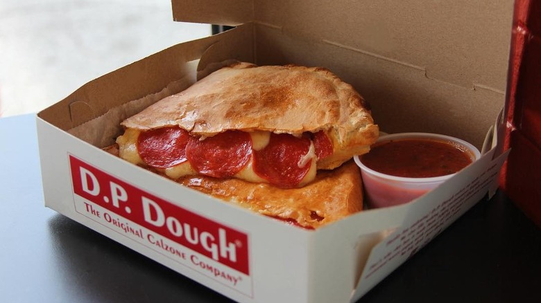 A pepperoni calzone from D.P. Dough in a takeout box with sauce