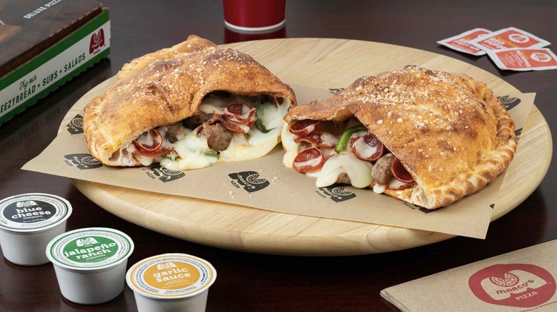 A calzone From Marco's Pizza cut in half on a wooden cutting board