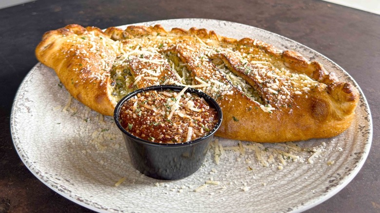 A calzone on a plate with marinara sauce at Rotolo's Pizzeria