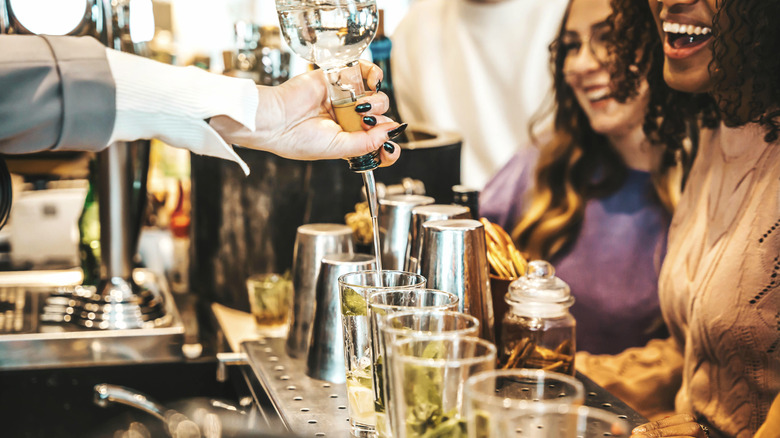 Hand pouring drinks at bar