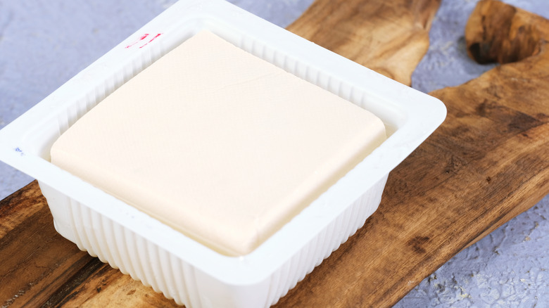 tofu in container on wooden slab