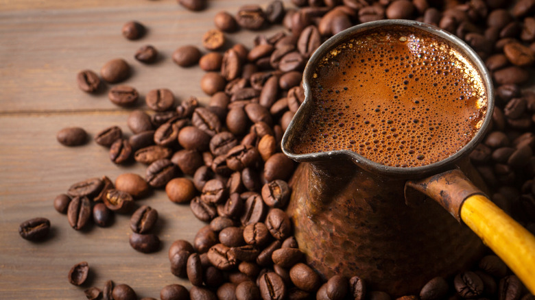 A container of coffee surrounded by coffee beans