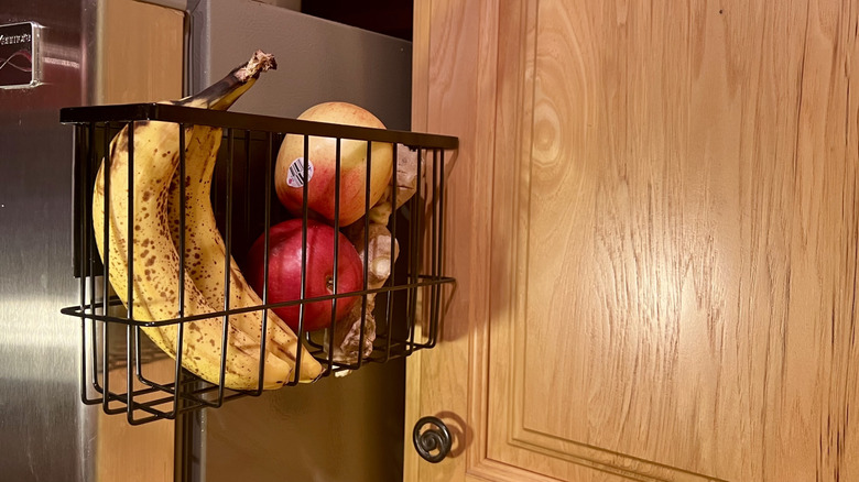 magnetic basket filled with fruit hanging on outside of fridge
