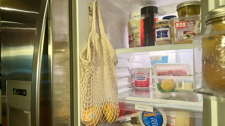 Mesh tote bag hanging from command cook inside refrigerator