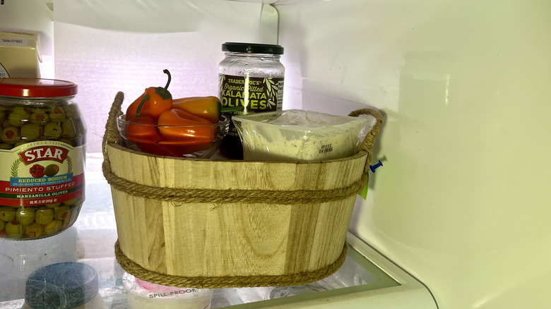 Wooden basket filled with snacks on refrigerator shelf