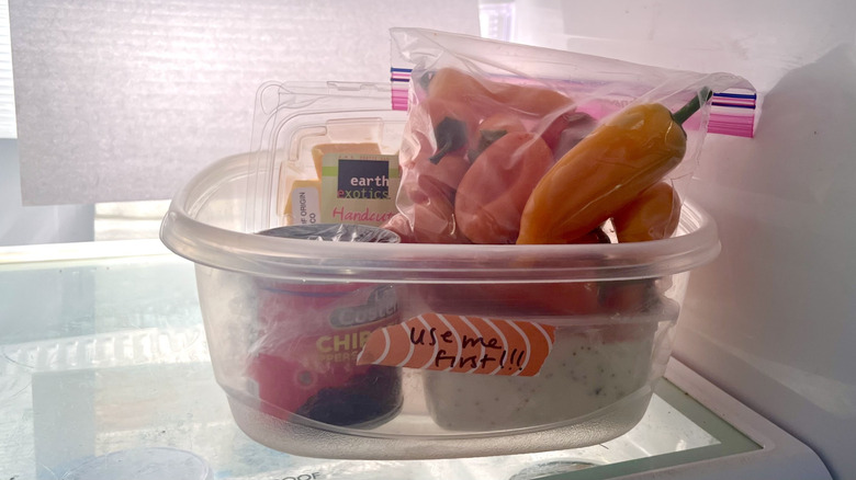 plastic container labeled "use me first" with various opened jars and bags