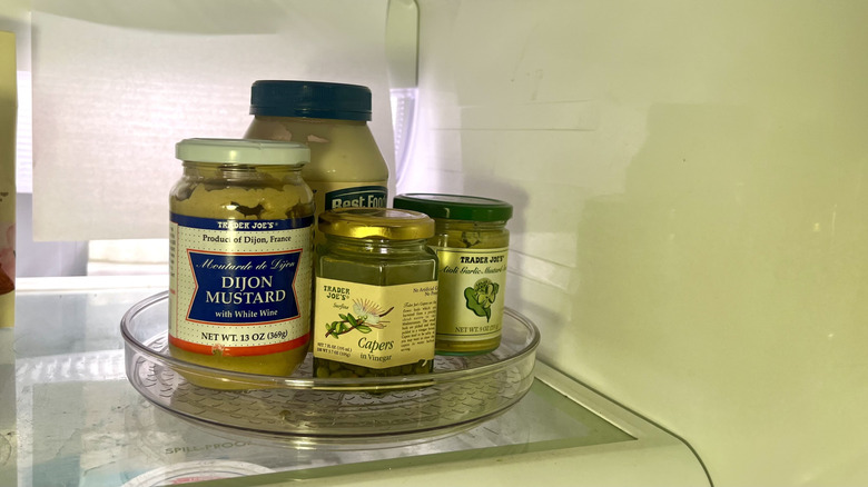 Lazy Susan sitting on refrigerator shelf with condiments in it