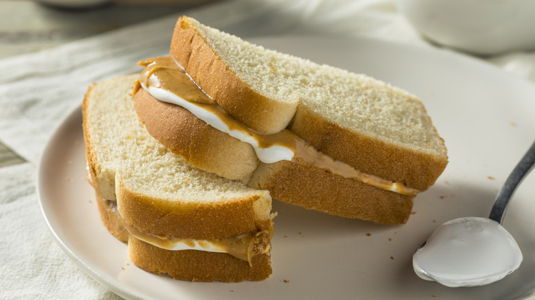 A peanut butter and frosting sandwich sits on a white plate