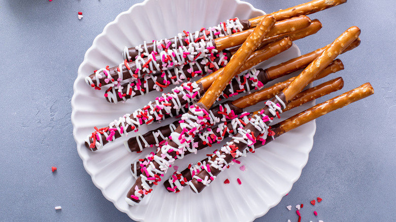 Pretzel rods coated in chocolate frosting and sprinkles