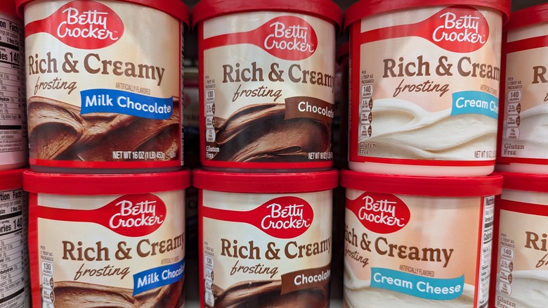 Cans of frosting sit on a grocery store shelf