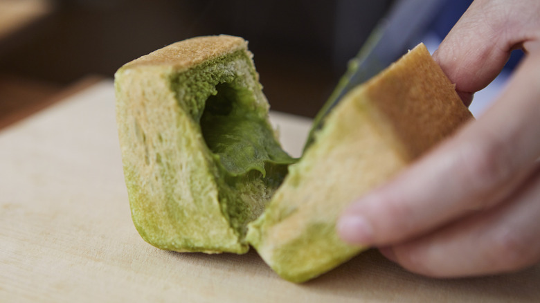 person slicing matcha white bread