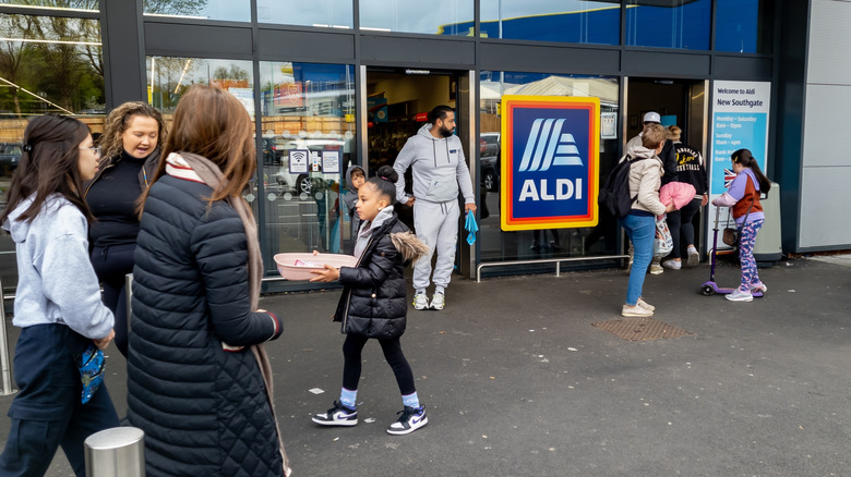 Several people walking into and out of an Aldi