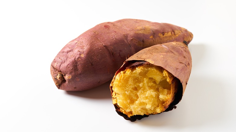 Two baked Japanese sweet potatoes on a white surface