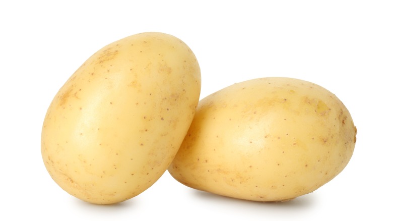 Two white potatoes on a white surface