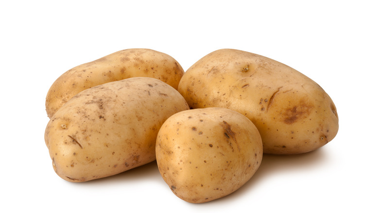 Three Yukon gold potatoes on a white surface