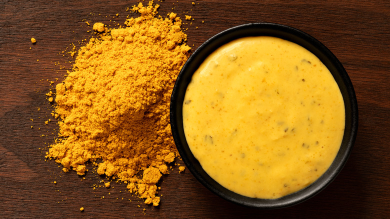 Curry sauce in black ramekin beside curry powder